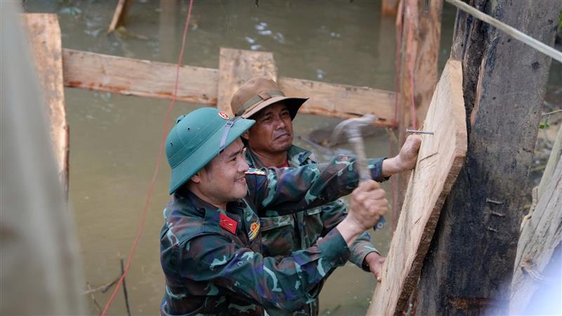Cán bộ, chiến sĩ lực lượng vũ trang huyện Đam Rông giúp người dân Tiểu khu Đạ Mpô (Thôn 5, xã Liêng S'rônh, huyện Đam Rông) dựng lại cây cầu Đạ Mpô