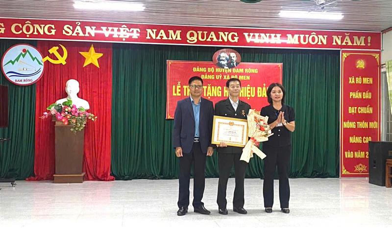 Đồng chí Trần Phú Vinh - UVBTV, Trưởng Ban Tuyên giáo Huyện ủy, Giám đốc Trung tâm Chính trị huyện và Đồng chí Phan Thị Cẩm - HUV, Bí thư Đảng ủy xã Rô Men trao Huy hiệu 45 tuổi Đảng cho đồng chí Nguyễn Văn Luyên